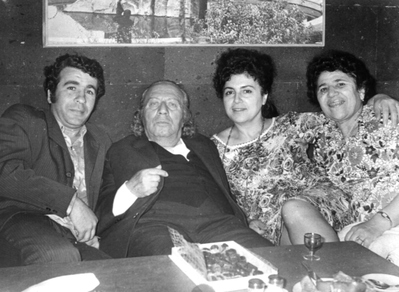 Ե. Քոչարը  մի խումբ մարդկանց  հետ՝ կողք-կողքի նստած. ձախից`  Անդրանիկ Հարությունյան, Երվանդ Քոչար, Լուիզա Սամվելյան և Մանիկ Մկրտչյան, [1970–ականներ]