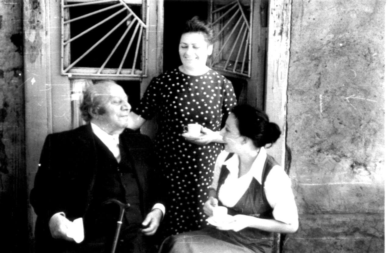 Ե. Քոչարը հյուրասիրության ժամանակ՝ երկու կանանց հետ զրուցելիս